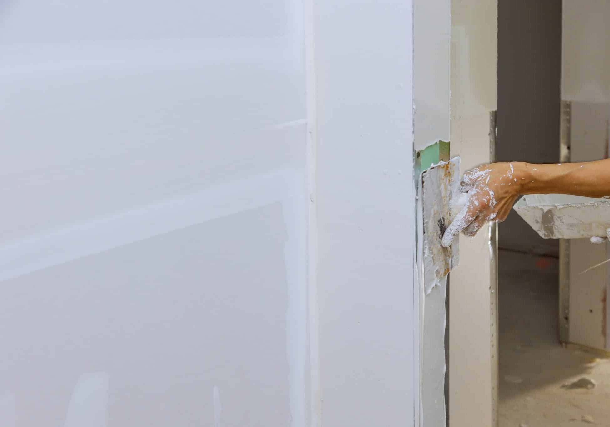 Worker spreading coating plaster the walls with putty